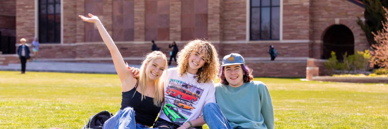 Three students hanging out at Farrand Field on a sunny day.