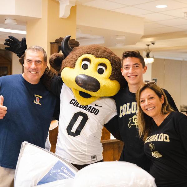 Photo of a student posing with Chip and his family at move-in.