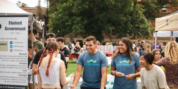 Photo of a student talking with members of a campus student organization while they all laugh together.