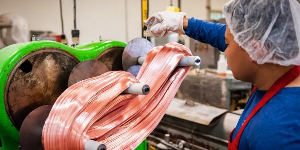 Photo of a worker pulling candy on a large machine.