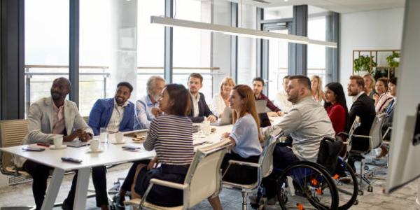 Photo of a group of people sitting in on a committee meeting around a table.