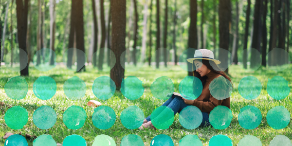 Photo of a student reading peacefully in a grassy area.