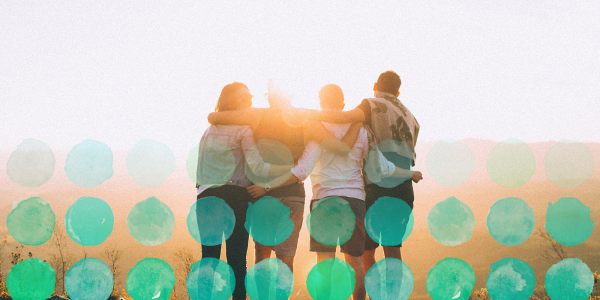 Photo of friends posing for a group photo in front of a sunset.