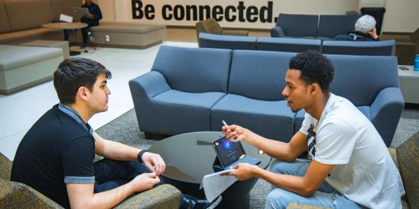 Photo of a student talking with a Peer Wellness Coach in the lobby of the CASE building.
