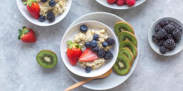 Overhead photo of colorful food plates, including oatmeal, berries and kiwis.