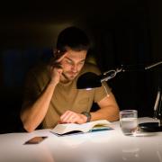 Photo of a student staying up late to study in a dark room with a lamp.