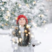 Photo of a student throwing snow into the air surrounded by twinkle lights.