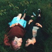 Photo of two people laying together in the grass. 