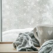 Cup of tea and blanket in front of snowy window