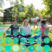 Group of students sitting on the grass at Kittredge Pond smiling.