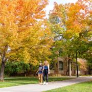 Photo of two students walking through Norlin Quad in the fall. 