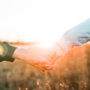 Two people holding hands in front of sunset