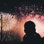 Silhouette of a man standing in front of a firework display.