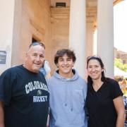 Photo of parents standing with their student in front of a residence hall.