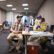 Man sitting at the COVID-19 vaccination clinic at CU Boulder.
