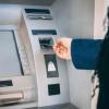 Photo of a person inserting their debit card into an ATM machine.