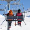 Photo of two skiers riding a chairlift together.