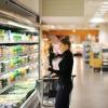 Photo of a woman checking the price tag of a smoothie drink at the grocery store.
