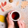 Photo of a person enjoying a mug of tea with fall decor.