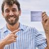 Photo of a young man holding up his vaccination card.