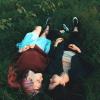 Photo of two people laying together in the grass.