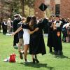 Photo of students posing for a photo with their graduation caps raised above their heads.