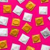 Photo of different colored condom wrappers over a solid pink background.