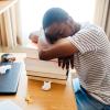 Student sleeping at his desk on a pile of textbooks