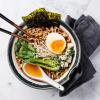Bowl of ramen noodles in broth with eggs, seaweed and bok choy