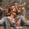 Girl throwing colorful fall leaves in the air in front of her face. 