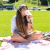 Photo of a student sipping on a coffee and enjoying a sunny day on the Business Field.