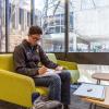 Photo of a student studying in front of a wall of glass.