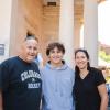 Photo of parents standing with their student in front of a residence hall.
