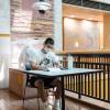 Student sitting at a desk in the UMC wearing a mask and CU Buff t-shirt as they flip through a notebook.