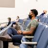 Students in masks sitting in a large lecture hall.