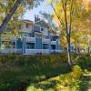Photo of a house in front of fall colored trees off campus.