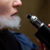 Girl holding a box vape while exhaling vapor on a cold day.