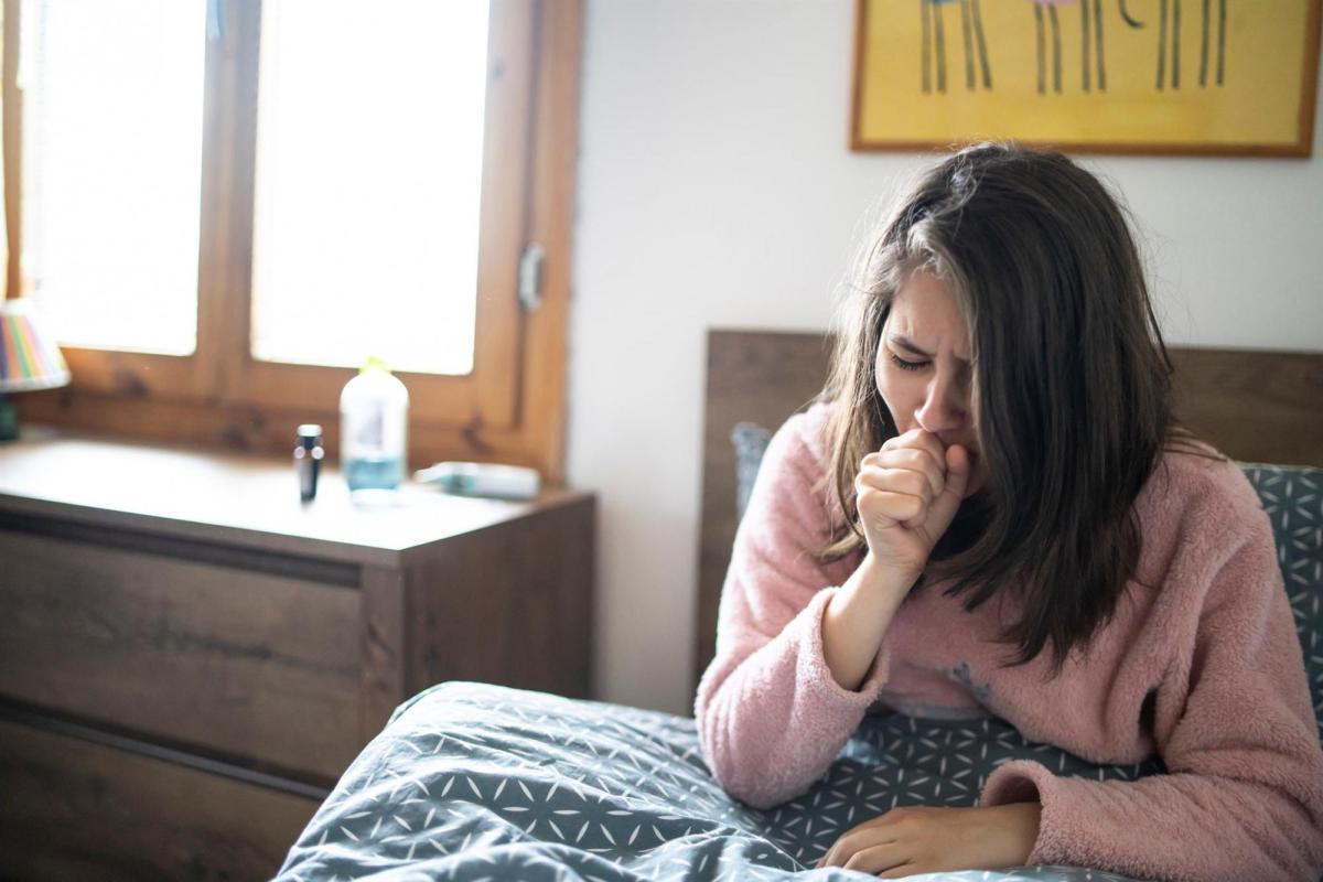 student in bed coughing