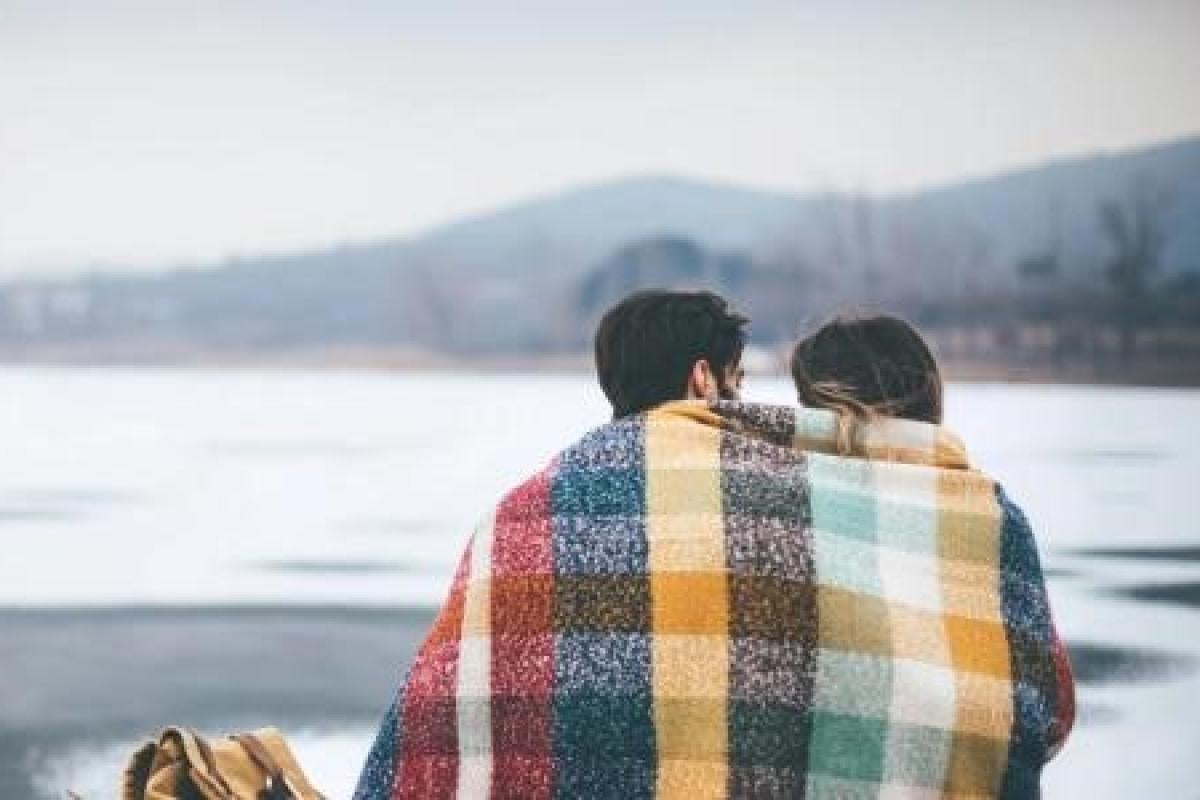 A couple sitting with a blanket around them