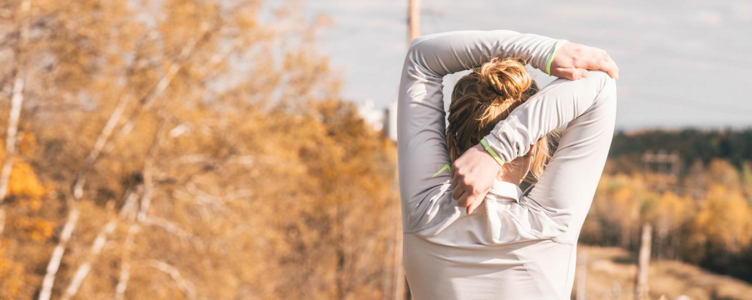 Women stretching shoulders before a run outside in fall