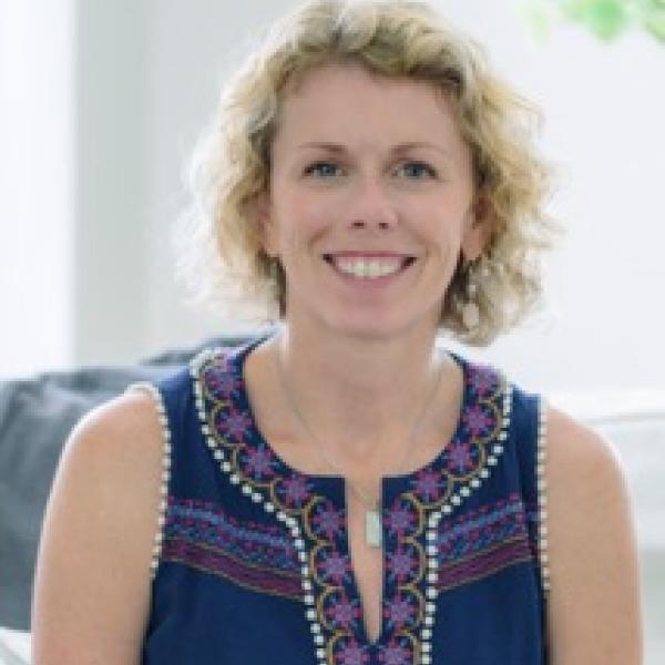 smiling woman in a blue shirt with blond curly hair