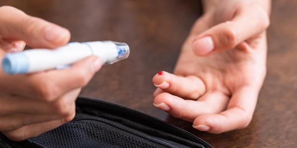 Photo of a person poking their finger with a lancet for a rapid HIV test.