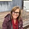 Sarah Jaquette Ray sitting down outside with jacket on and red scarf
