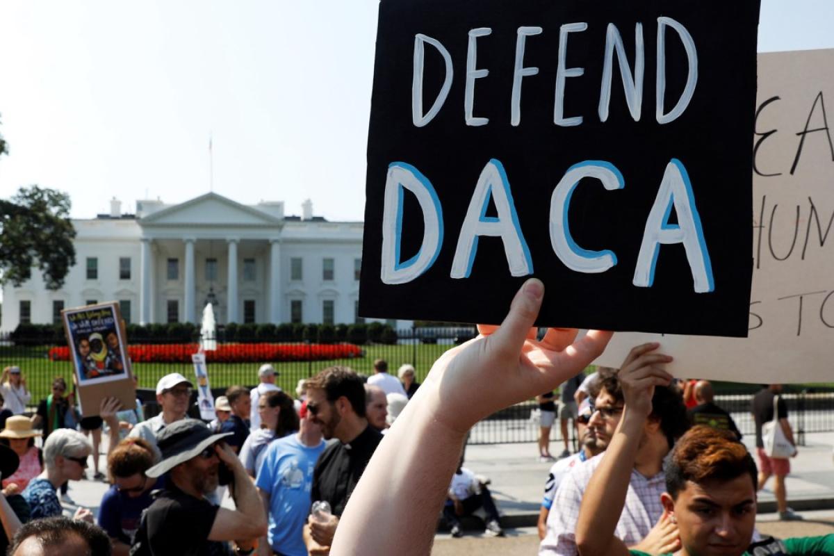 A protester holds up a sign that says "Defend DACA" in front of the White House.