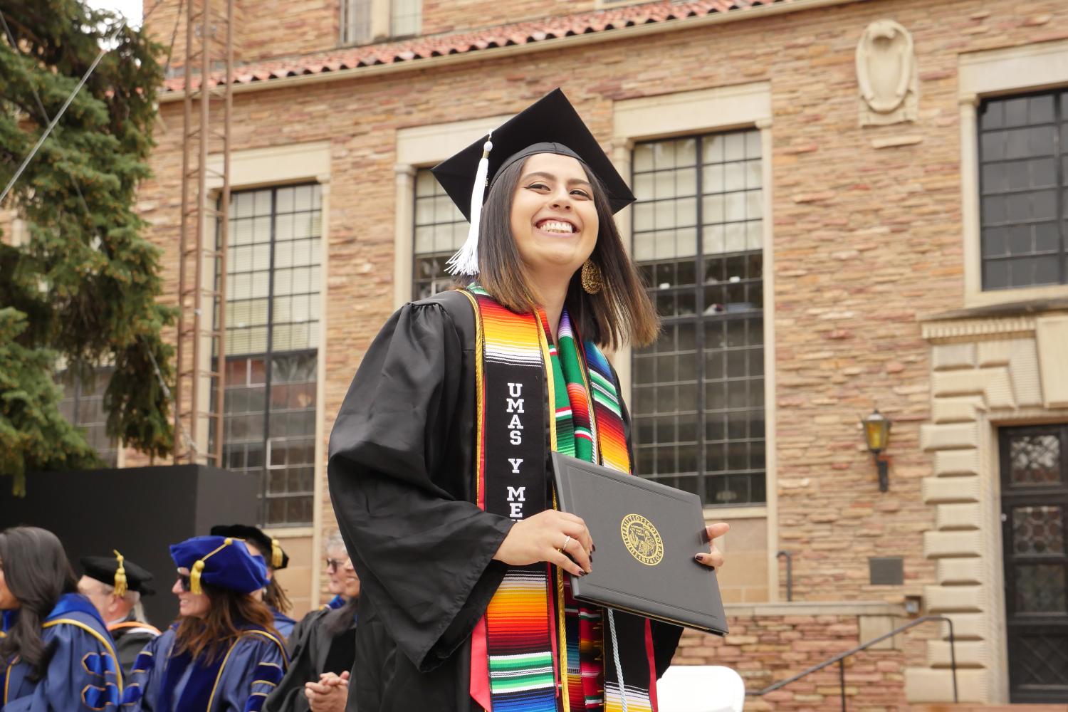 Student walking across graduation stage with diploma