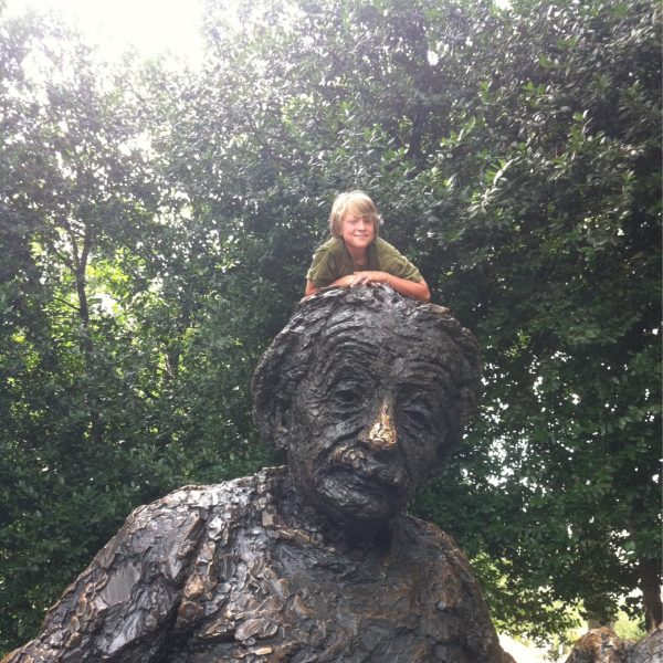 Clifford Adamchak sits on top of an Einstein statue.