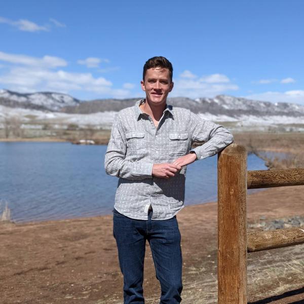 Dylan Anderson stands in front of a lake.