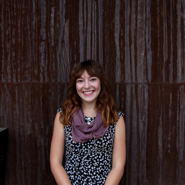 Eva Aneshansley stands in front of a wooden wall.