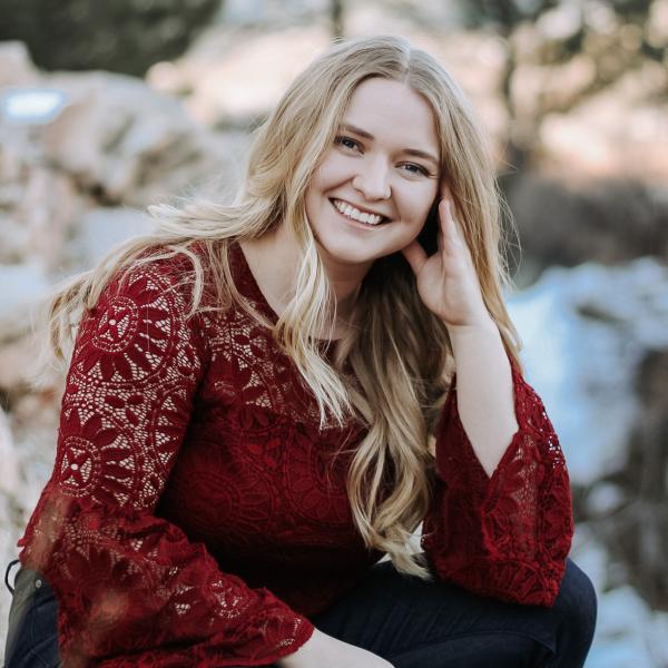 Hannah Beehler kneels in front of trees.