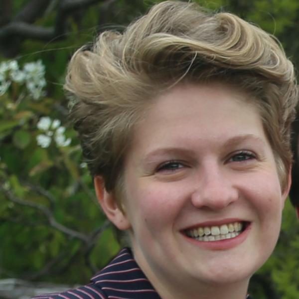 Rebekah Benjamin-Pollak stands in front of a tree. 